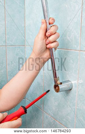 Residential plumbing repair closeup hands change wall mounted height adjustable shower bar slider rail holder.
