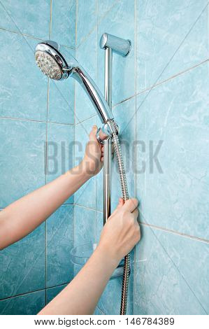 Replacing the plumbing in the bathroom close-up human hands installed hose with shower head in height adjustable shower bar slider rail.