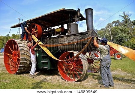 ROLLAG, MINNESOTA, Sept 1. 2016: Unidentified men demonstrate the placing of a belt on an old steam engine fly wheel during the West Central Steam Threshers Reunion in Rollag, MN.