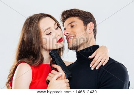 Sensual young couple hugging and posing with gun