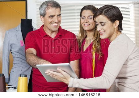 Happy Tailors Using Tablet Computer In Factory