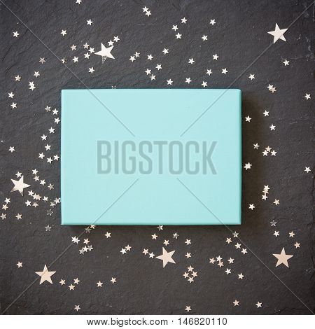 rectangular light blue box on black background with silver stars decorations. Holiday greetings. Engagement. turquoise on black board.