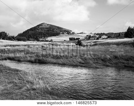 Conical mountain Bukovec above Jizerka village and Jizerka creek, Jizera Mountains, Czech Republic . Black and white image.