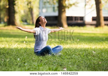 Beautiful businesswoman enjoys in the park with her arms outstreched.