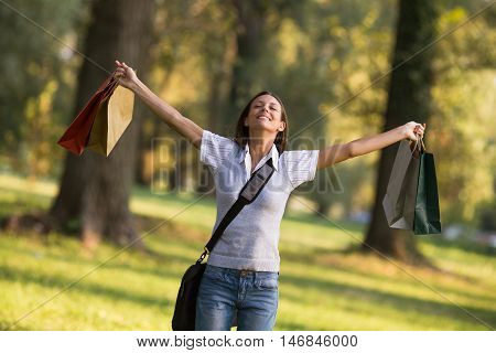 Beautiful businesswoman enjoys in the park with her arms outstreched after shopping.