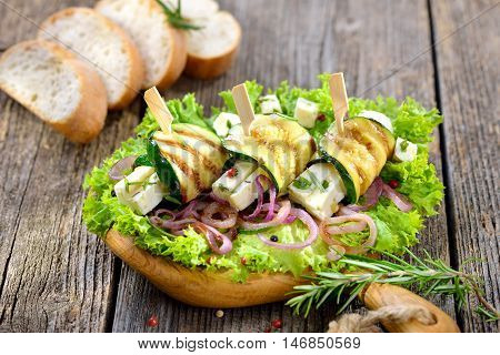 Delicious Greek appetizers: Grilled zucchini rolls with feta cheese and herbs on roasted onion rings and green salad