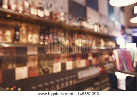 Blurred back bar. Bottles of spirits and liquor at the bar. Blurred desk in bar.