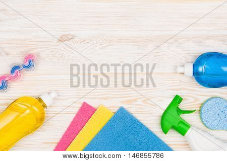 Cleaning items and tools lying on textured white floor background. Frame for cleaning concept or advertising. Empty copy space around products.