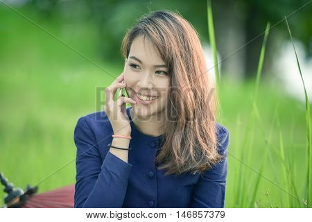 Asian woman wearing traditional dress sitting telephone.