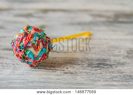 Cake pop with frosting. Bright glaze and sprinkles. Boost mood quickly and easily. See joy in colors.