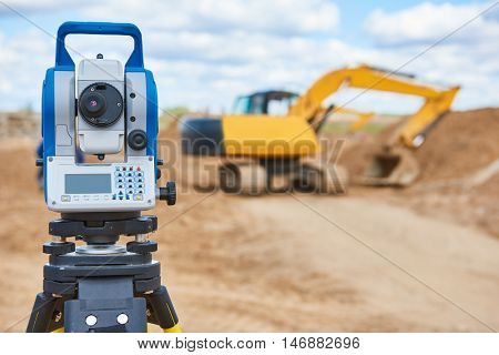 surveyor equipment theodolie at construction site with excavator