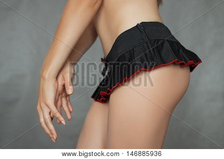 Beautiful young girl in a short skirt on gray background.