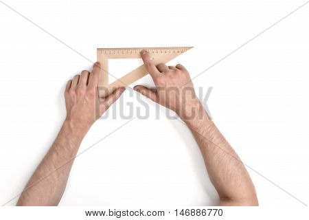 Man holding a wooden set square or right angle in the 90-60-30 conformation over a white background with copy space in a conceptual image , overhead view of his arms