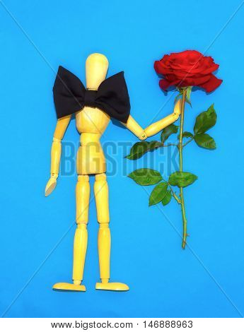 Red rose and figure wooden man on blue background
