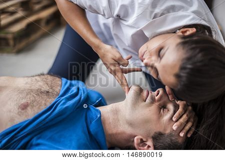 girl checking vital parameters of an unconscious man