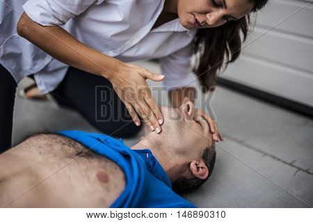 girl checking vital parameters of an unconscious man