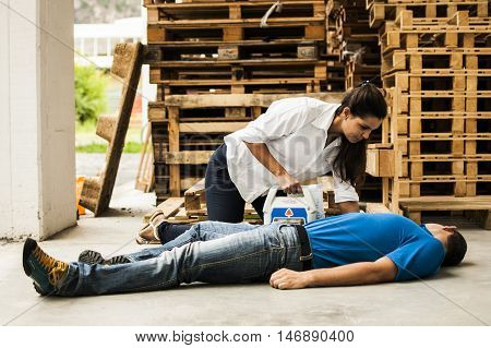 girl assisting an unconscious man with defibrillator