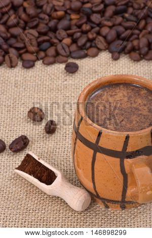 Vintage ceramic cup with coffee and milk on a jute with coffee beans in the background