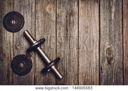 Old iron dumbbells or exercise weights with extra plates on an old wooden deck, floor or table. Image taken from above, top view. A lot of copy space around product