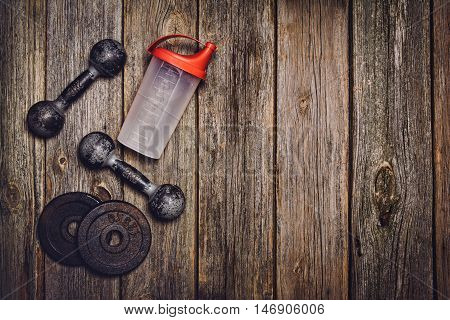 Old iron dumbbells or exercise weights with extra plates on an old wooden deck, floor or table. Image taken from above, top view. A lot of copy space around product