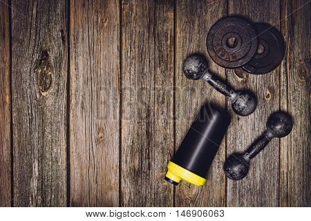 Old iron dumbbells or exercise weights with extra plates on an old wooden deck, floor or table. Image taken from above, top view. A lot of copy space around product