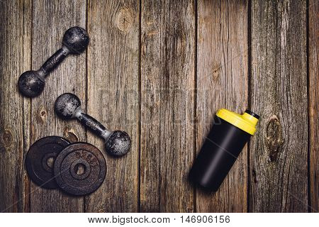 Old iron dumbbells or exercise weights with extra plates on an old wooden deck, floor or table. Image taken from above, top view. A lot of copy space around product