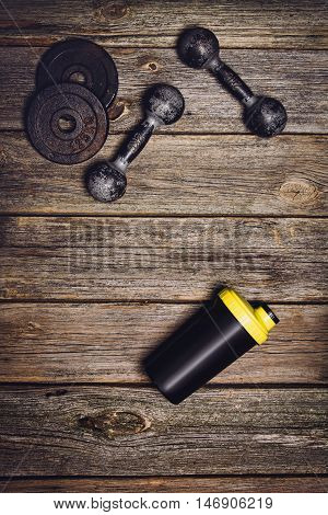 Old iron dumbbells or exercise weights with extra plates on an old wooden deck, floor or table. Image taken from above, top view. A lot of copy space around product