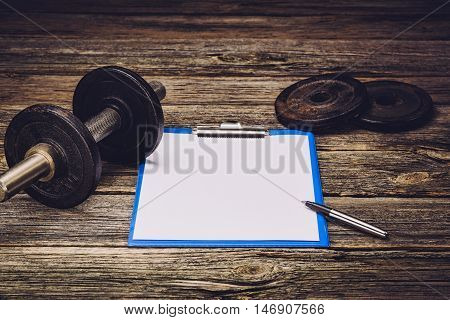 Old iron dumbbells or exercise weights with extra plates on an old wooden deck, floor or table. Image taken from above, low angle or top view. A lot of copy space around product