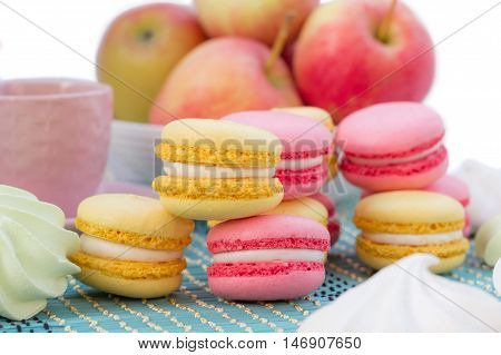Still life of served coffee cups macaroon cookies marshmallows and apples