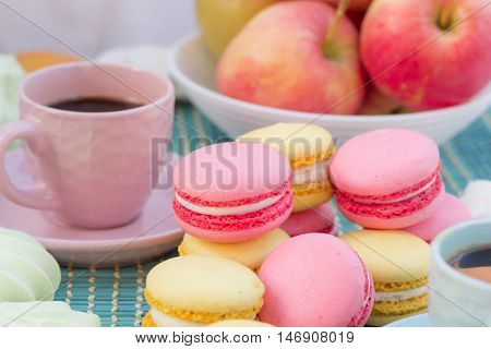 Still life of served coffee cups macaroon cookies marshmallows and apples