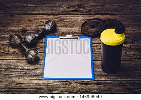 Old iron dumbbells or exercise weights with extra plates on an old wooden deck, floor or table. Image taken from above, low angle . A lot of copy space around product