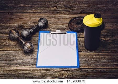 Old iron dumbbells or exercise weights with extra plates on an old wooden deck, floor or table. Image taken from above, low angle or top view. A lot of copy space around product