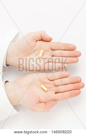 Male Doctor Holdling One Pill Over Each Of His Palms - Studio Shot