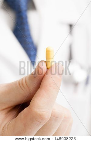 Male Doctor Holdling One Pill With His Fingers - Studio Shot