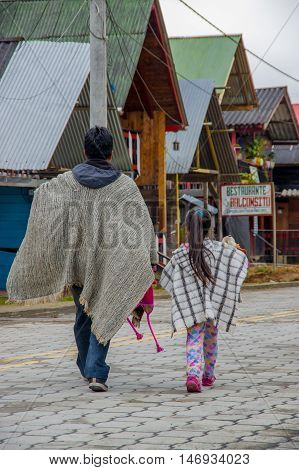 PASTO, COLOMBIA - JULY 3, 2016: man walking with a little girl dressed with traditional clothes in a small location in la cocha lake.