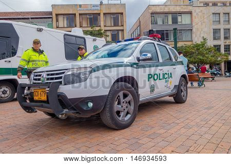 PASTO, COLOMBIA - JULY 3, 2016: unidentified police officers standing next to a police car parked on the central square of the city.