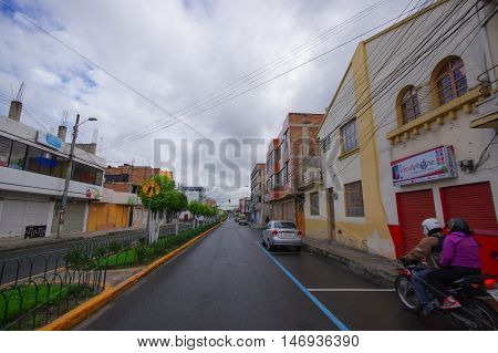 TULCAN, ECUADOR - JULY 3, 2016: man driving a motorcycle with a passenger on a small street of the city.