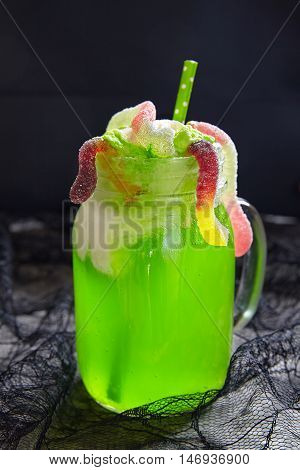 Green drink with ice cream float and gummy worms for Halloween