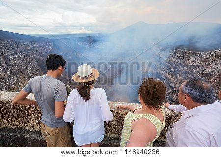 family of fourpeople look at volcano crater during vacations