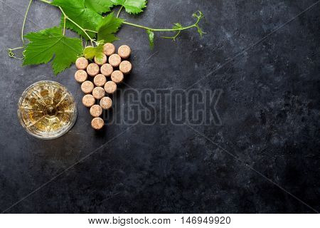 Wine corks grape shape, white wine glass and vine on stone table. Top view with copy space for your text