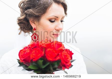 winter bride in beautirul fur shawl holding bouquet of red roses