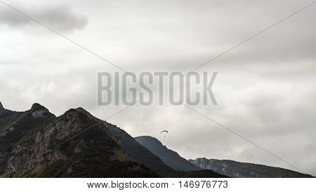 paraglinding from the mountain, flyng around the top, cloudy sky mountain landscape