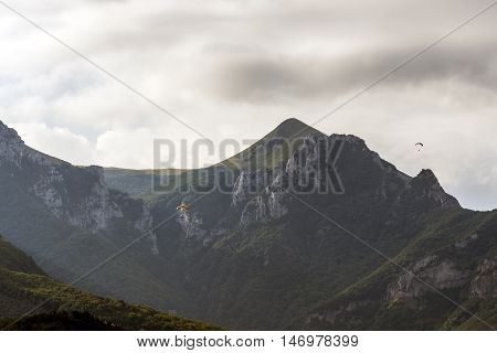 paraglinding from the mountain, flyng around the top, cloudy sky mountain landscape