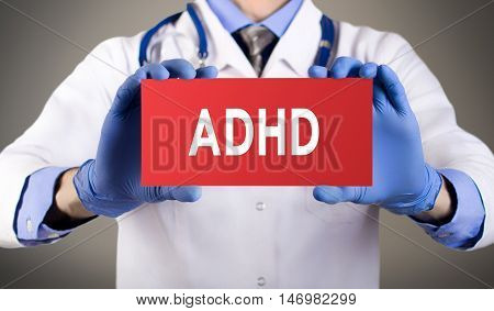 Doctor's hands in blue gloves shows the word ADHD (attention deficit hyperactivity disorder). Medical concept.
