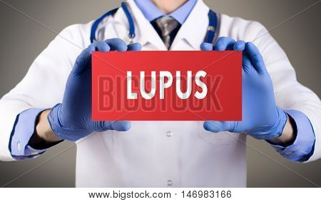 Doctor's hands in blue gloves shows the word lupus. Medical concept.
