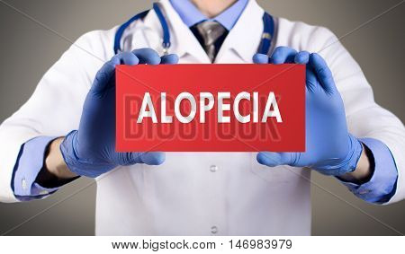 Doctor's hands in blue gloves shows the word alopecia. Medical concept.