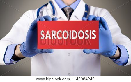 Doctor's hands in blue gloves shows the word sarcoidosis. Medical concept.