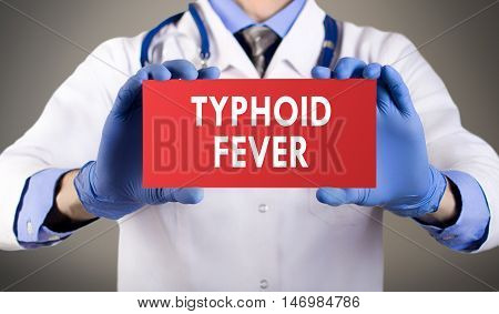Doctor's hands in blue gloves shows the word typhoid fever. Medical concept.