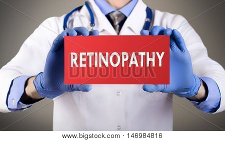 Doctor's hands in blue gloves shows the word retinopathy. Medical concept.