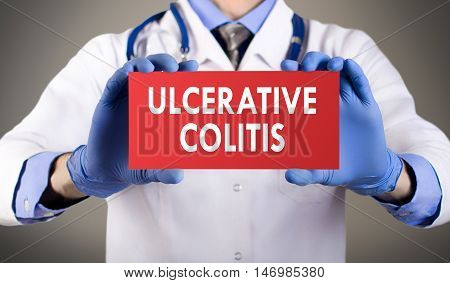 Doctor's hands in blue gloves shows the word ulcerative colitis. Medical concept.